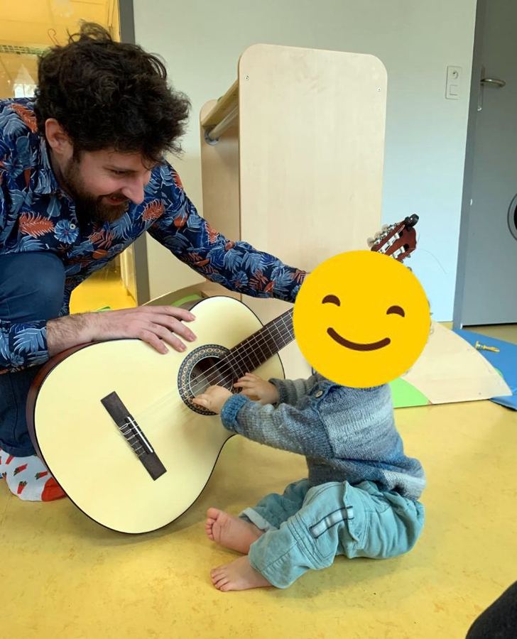 Un tout-petit découvre les cordes de la guitare